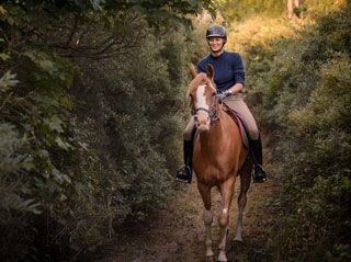 Equithérapie dans le cadre de la sclérose en plaques : une jeune femme à cheval.