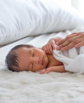 Un bébé enveloppé dans une couverture sur un lit