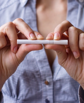 Jeune femme tenant une cigarette de bout à bout